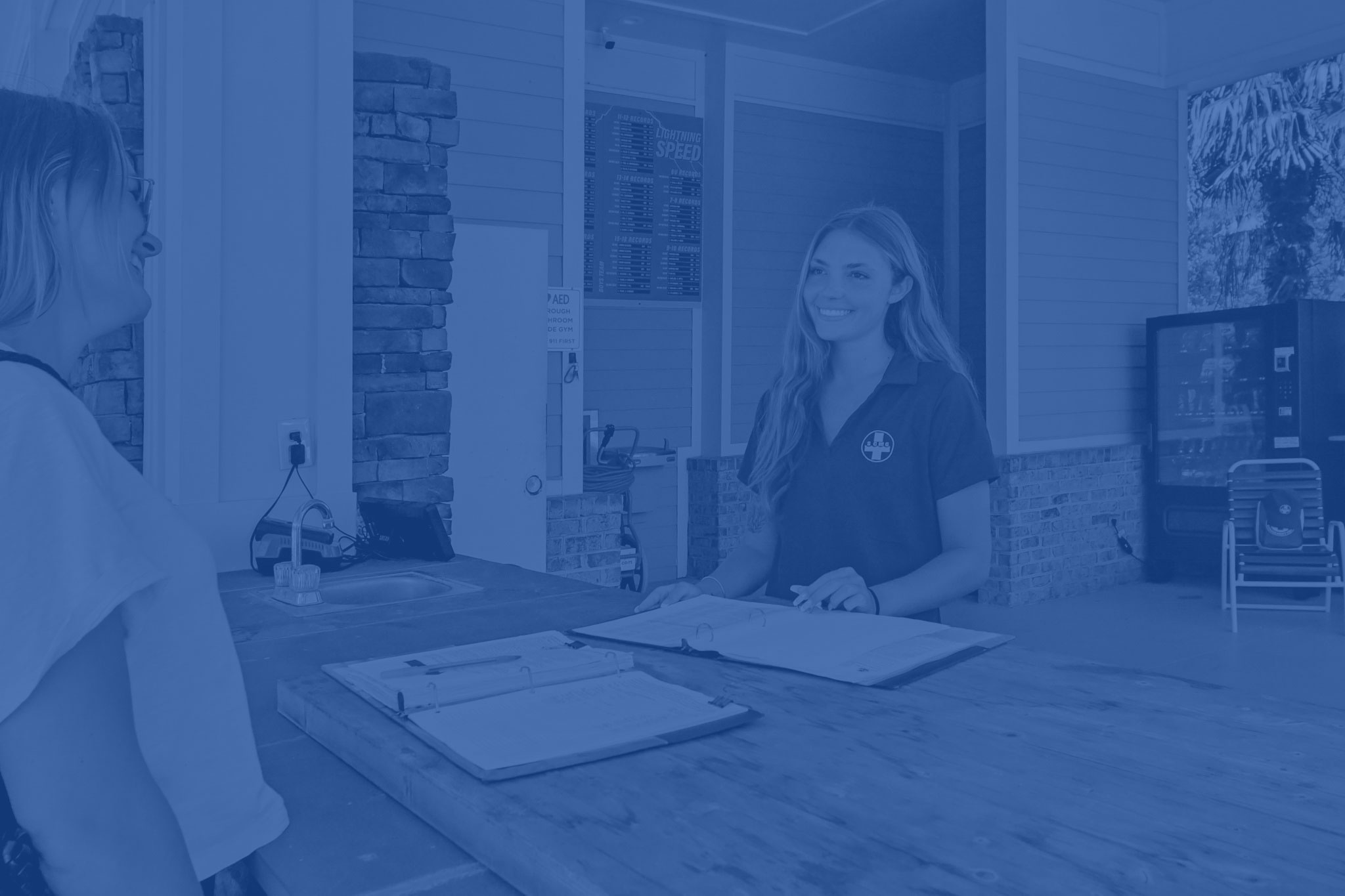 Female SCMG employee checking in patrons at the front desk