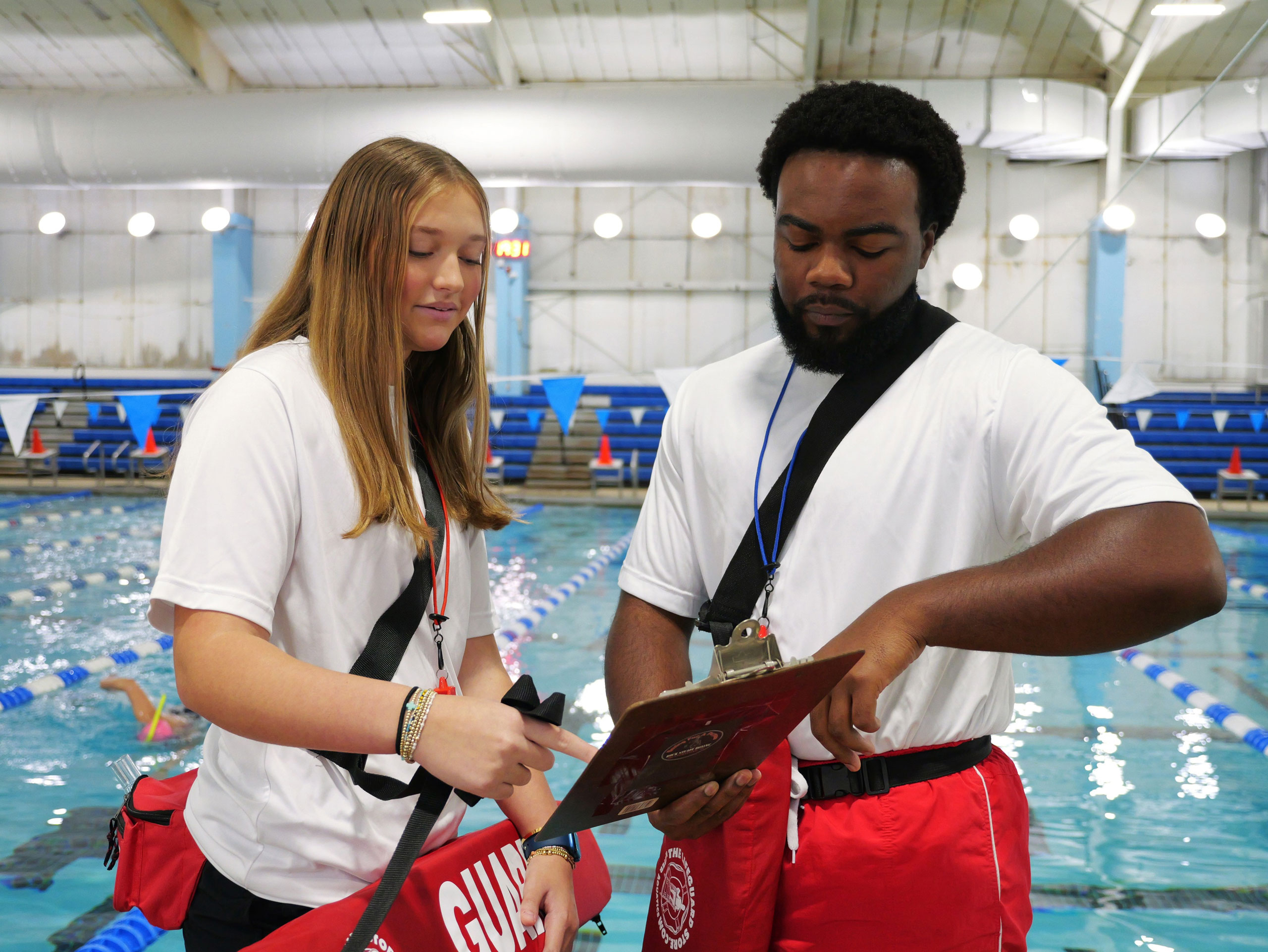 Female and male lifeguard going through a checklist on the pool deck