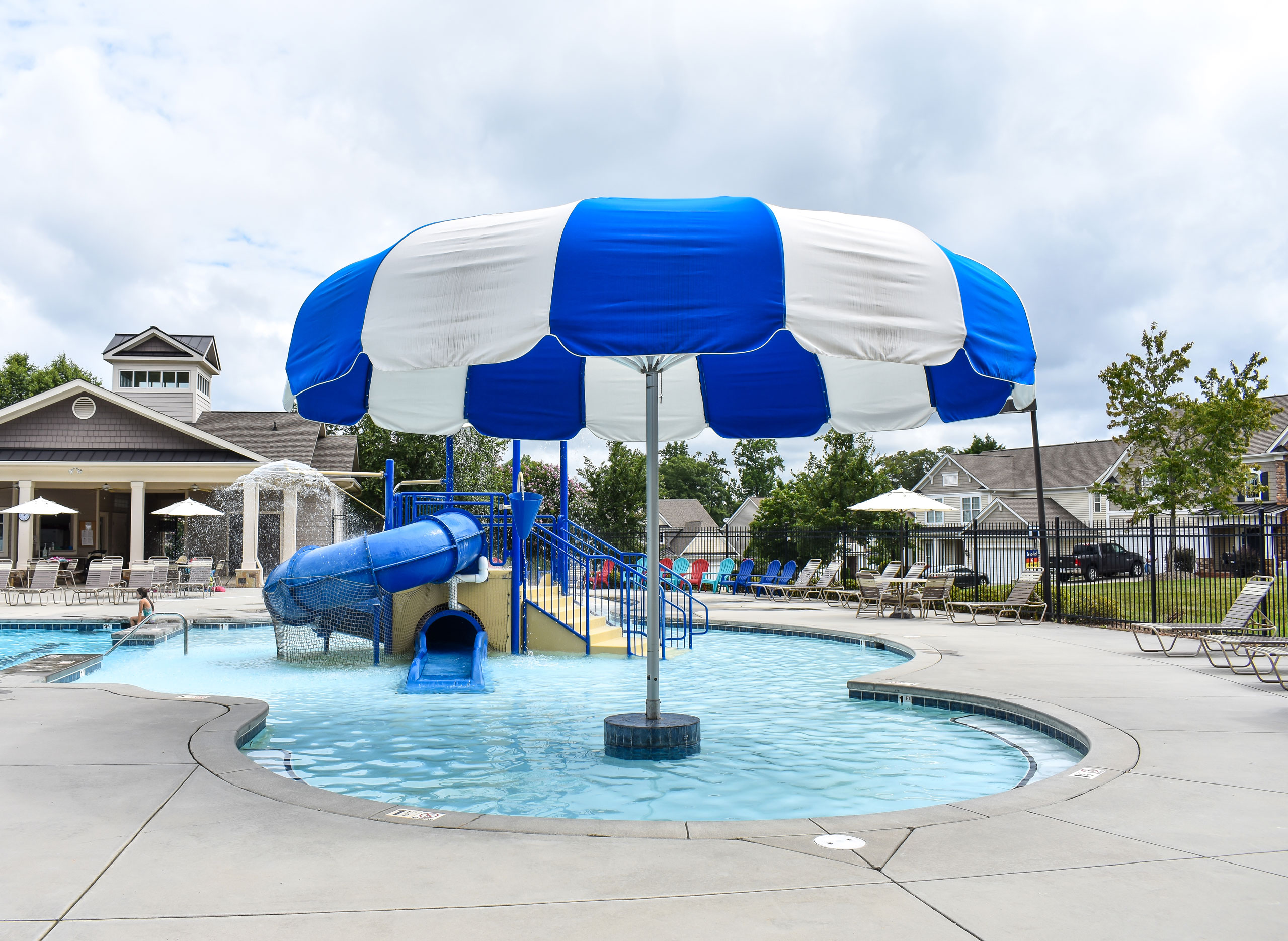 Large blue and white umbrella covering a youth area of a community swimming pool